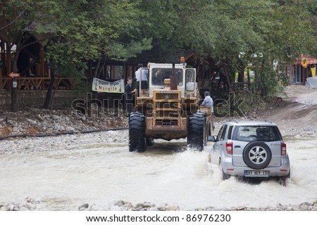 OLYMPOS, TURKEY - OCTOBER 14: Bulldozer and Off-Road Vehicle cross flooded road after flood disaster on October 14, 2009 in Olympos, Turkey. The floods destroy roads and houses.