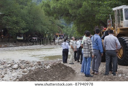 OLYMPOS, TURKEY - OCTOBER 14:  Politicians and civil servants waiting for earth mover used  as a ferry for crossing overflooded road after flood disaster on October 14, 2009 in Olympos, Turkey.