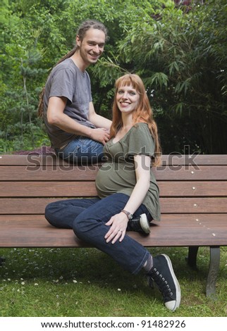 Young Couple sitting on a Bench - The woman is is eight months pregnant.