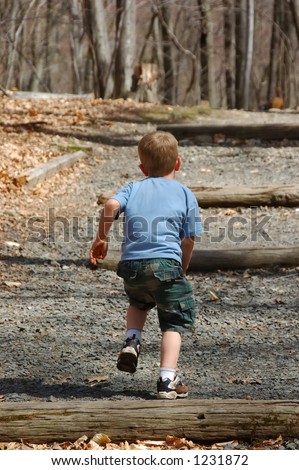 Little boy running up wooded gravel steps.  He is wearing camo shorts and a blue shirt.  There is dappled sunshine.