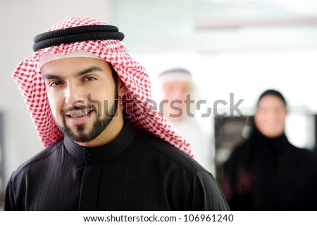 Confident young Saudi business executive with his team in the background
