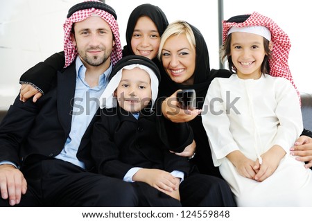 Arabic Muslim family father and mother with children watching television