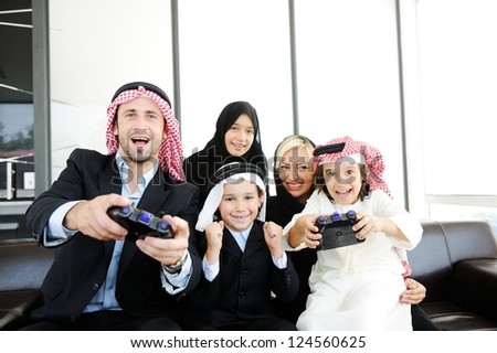 Happy Arabic family playing at home with video game controllers