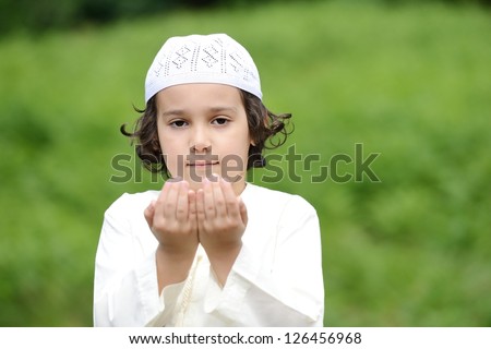 A little Arabic boy praying outdoor in nature