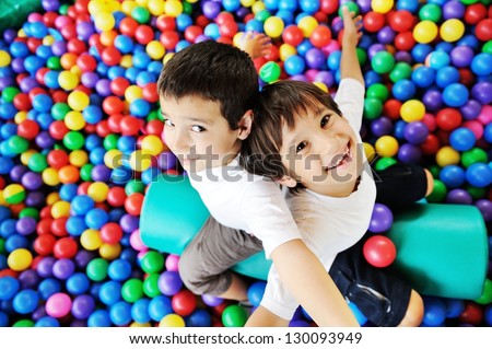 Little smiling boy playing lying in colorful balls park playground