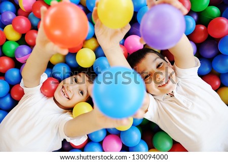 Happy children playing together and having fun at kindergarten with colorful balls
