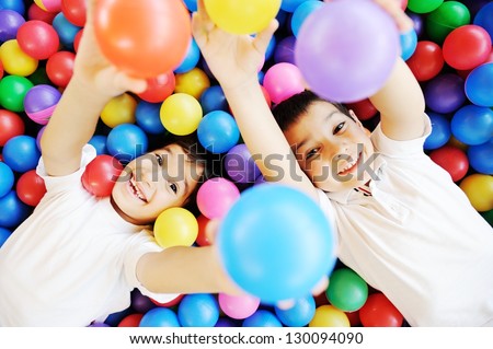 Happy Children Playing Together And Having Fun At Kindergarten With Colorful Balls