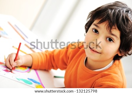 Cute little schoolboy drawing an house and looking at camera
