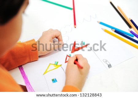 Childrens hand with pencil draws the house