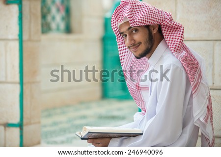 Young Arabic Muslim man reading Koran and praying