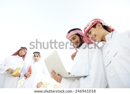 Happy group of Middle eastern Gulf boys using laptop