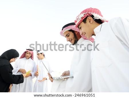 Happy group of Middle eastern Gulf boys using laptop