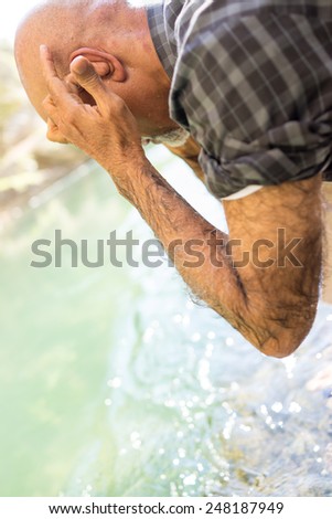 Senior Arabic Pakistani man having islamic religious rite ceremony of ablution face washing