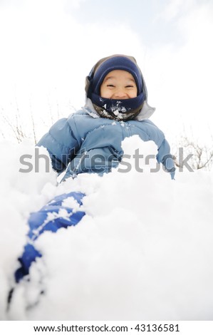 Child playing in the snow with snow on his face and leg