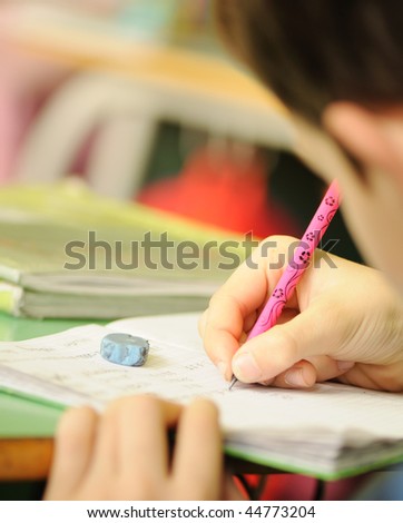 Kid in classroom with pen in hand