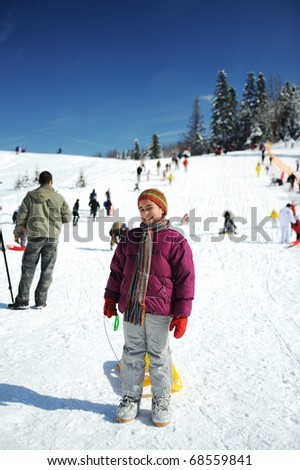 Winter games, happiness on snow on mountain, little girl and many people behind her
