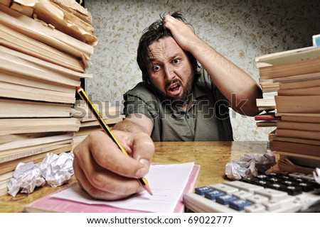Businessman in problems. Alone working in office with a lot of books around on messy table. Yelling and screaming for bad results.