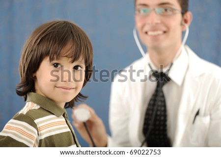 Male doctor examining a child patient in a hospital and kid looking at camera