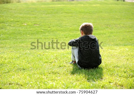 Sad abandoned orphan sitting in nature and contemplating, autism syndrome