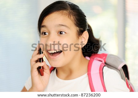 School girl with cell phone, talking and smiling