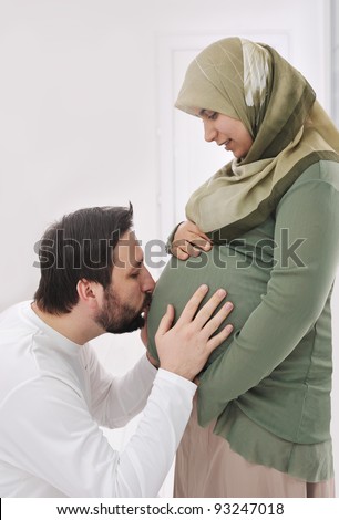 Pregnant  muslim  wife smiling with her  husband kissing belly,and his hands on belly