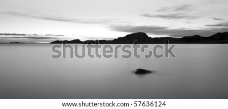 Black and white picture with rocks by the ocean.