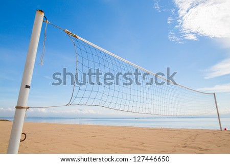 A beach volleyball net on the beach with a clear and sunny sky