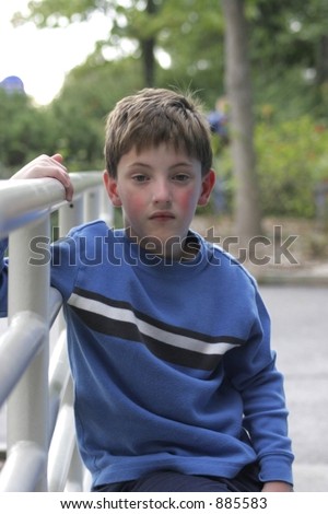 Boy sitting on hand rail looking thoughtful or sad.