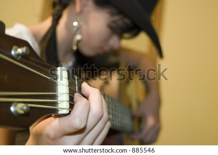 Young teenage girl playing guitar with focus on hand using frets.