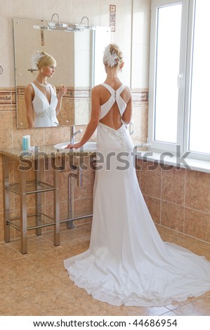 Beautiful blonde bride looking in the mirror.