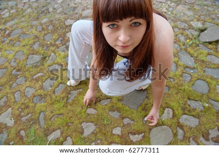Close-up of young red-haired woman squatted down on the pavement.