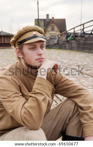 Soldier in uniform of World War I, sit down, resting on the pavement and smoking. Costume accord the times of World War I. Photo made at cinema city Cinevilla in Latvia.