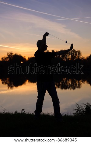 Silhouette of Yo-Yo player on the lake shore