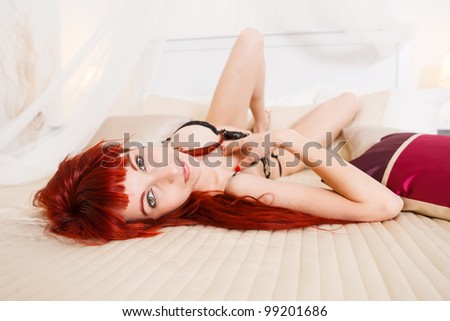 Gorgeous young redhead relaxing in bed with beige and purple pillows. Check also my other pictures with the model!