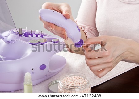 Manicure with electric manicure set on female hands.