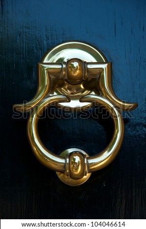 Close-up of a classic brass door knocker on a black door