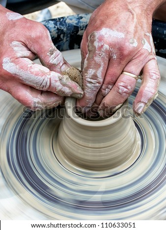 Potter spinning and shaping wet clay in the shape of a cup