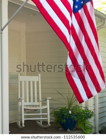 Vintage scene of rocking chair and US flag on front porch