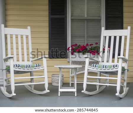 Two classic American rocking chairs on the front porch of a home.