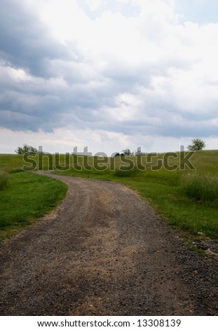 Old gravel road in pasture running off to horizon - vertical photo
