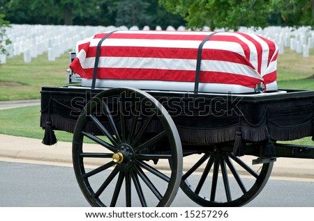 Flag draped casket on caisson being pulled to grave site in Arlington National Cemetery with grave stones in background