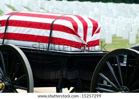 Flag draped casket on caisson being pulled to grave site in Arlington National Cemetery with grave stones in background