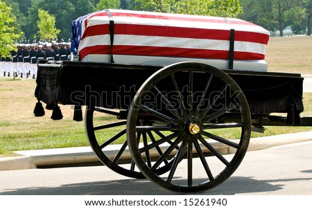 Funeral at Arlington National Cemetery with caisson carrying flag draped casket and military honor guard in background