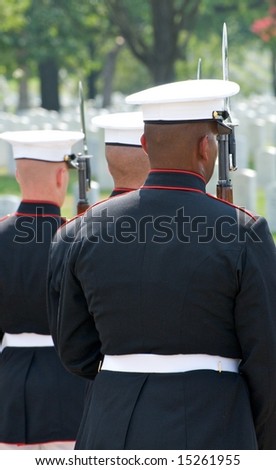 Funeral at Arlington National Cemetery with with military honor guard in foreground and gravestones in background