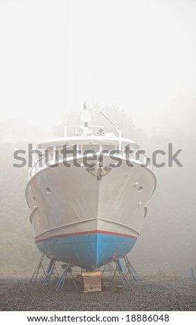 Vertical photo of yacht out of water for season surrounded in fog