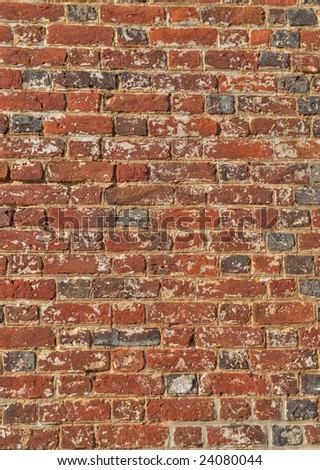 Vertical photo of old brick wall with rough, peeling bricks and paint