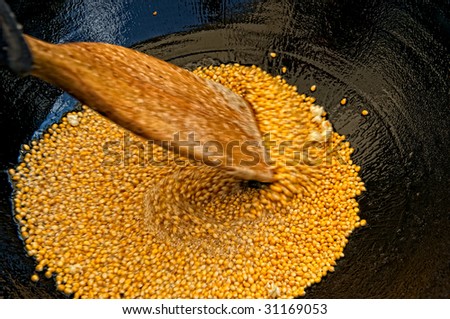 Kettle corn being rapidly stirred before sugar is added
