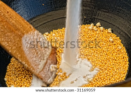 Kettle corn being stirred while sugar is added