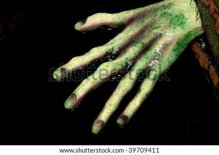 Wet and bony hand of a zombie ready to grab someone on Halloween