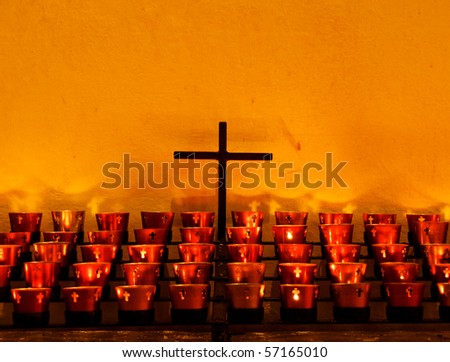 Crucifix and red candle holders with cross in Catholic church against old adobe wall